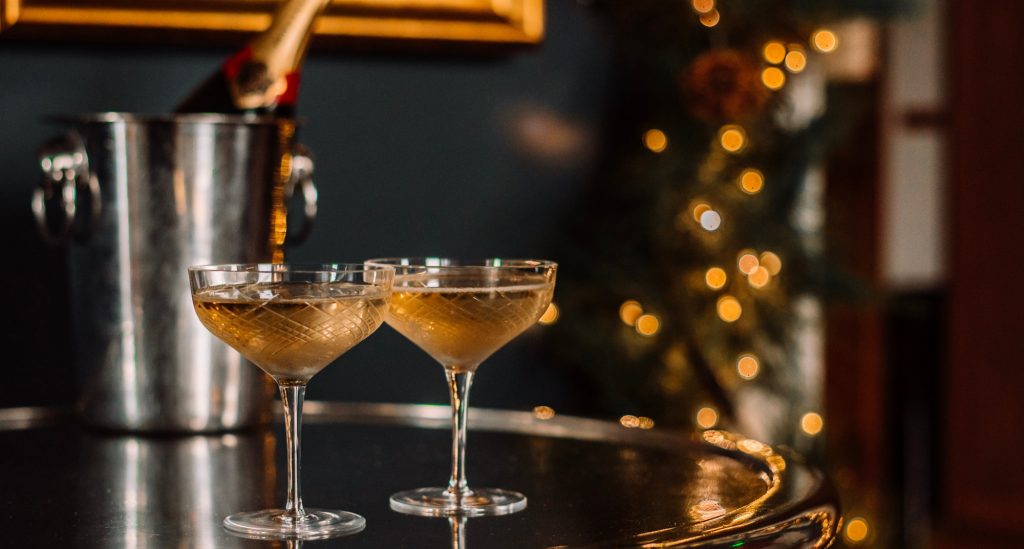 Two glasses of champagne in front of a bottle in an ice bucket - festive menus at GNH